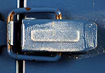 Fingerabdrücke auf einem Metallwerkzeugkasten mit Instant Weiß sichtbar gemacht
